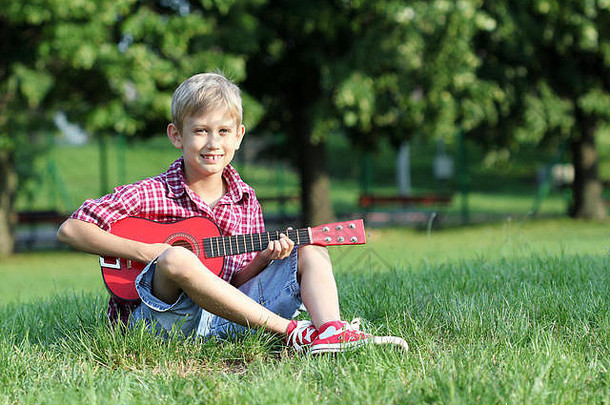 快乐男孩坐着草玩吉他