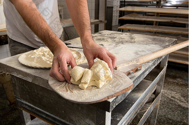 厨师们用手在面包房的<strong>木皮</strong>上用特写镜头塑造烤面包用的面团