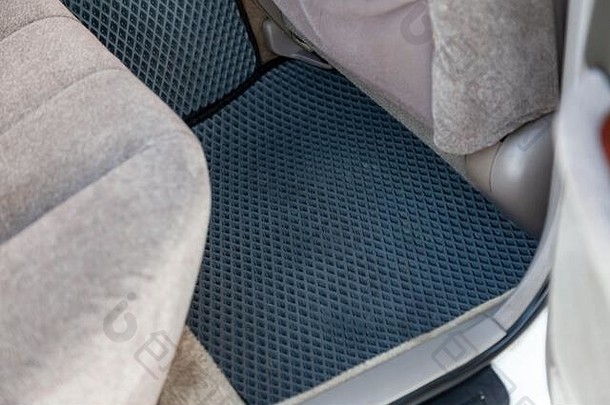 在车间清洁乘客座椅下的黑色橡胶汽车地板垫，以便对车辆进行干洗。汽车服务业。内河