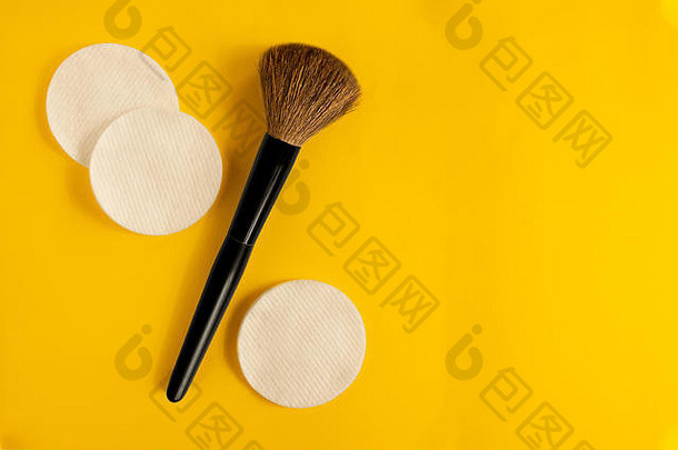 黄色背景上的化妆刷和清洁海绵，并留有复印空间。时尚美容师或家用化妆品使用仪器