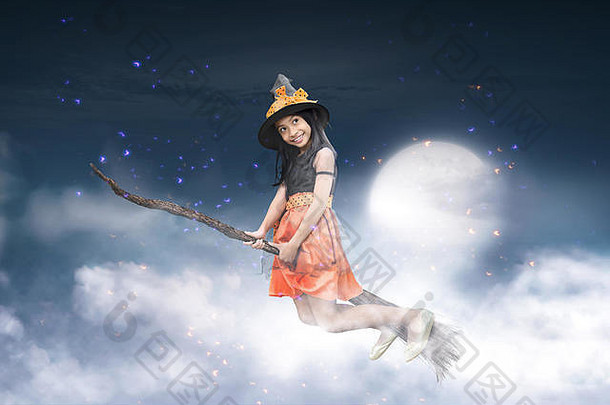 快乐的亚洲女巫骑着扫帚在月光下飞翔