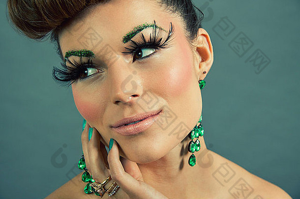深色皮肤的女人，戴着绿色珠宝和灰色背景的饰物