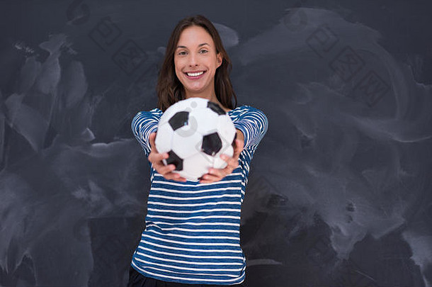 一名年轻女子手持足球在粉笔画板前的肖像