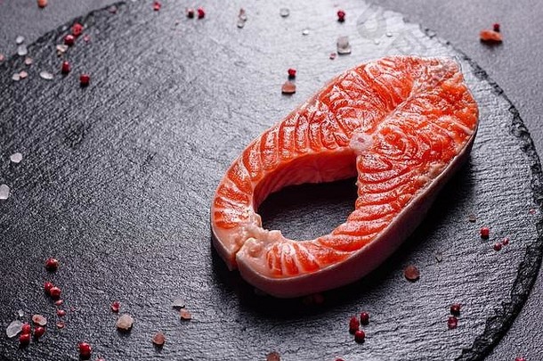 生鳟鱼红鱼牛排配香草、柠檬和橄榄油，深色背景。烹饪鲑鱼，海鲜。健康饮食观念