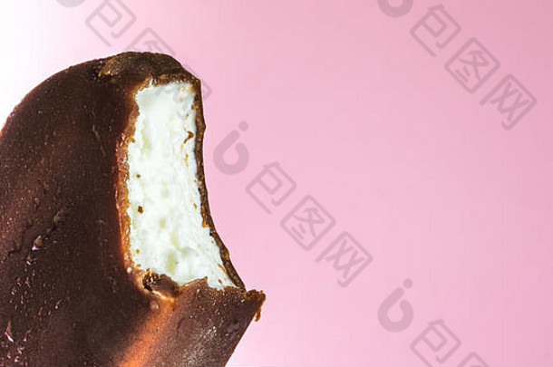 巧克力釉中的咬冰激凌棒棒糖特写镜头，柔和的粉红色背景上有冷凝物和糖霜。冰淇淋的质地。
