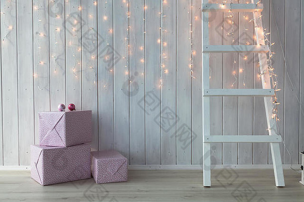 在白色木质背景上点燃的圣诞灯，还<strong>有</strong>粉红色的礼品盒和楼梯