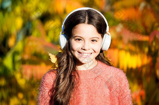 享受秋天。公园散步的好天气。她热爱自然和音乐。<strong>开学季</strong>节。秋天的心情。小女孩听有声书。戴着耳机的小孩。在线教育。儿童电子书。