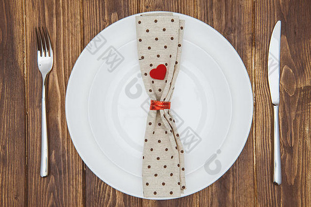 情人节晚餐套装，刀，叉，餐巾和盘子放在木桌上