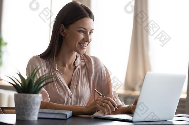 微笑年轻的女人工作移动PC使笔记