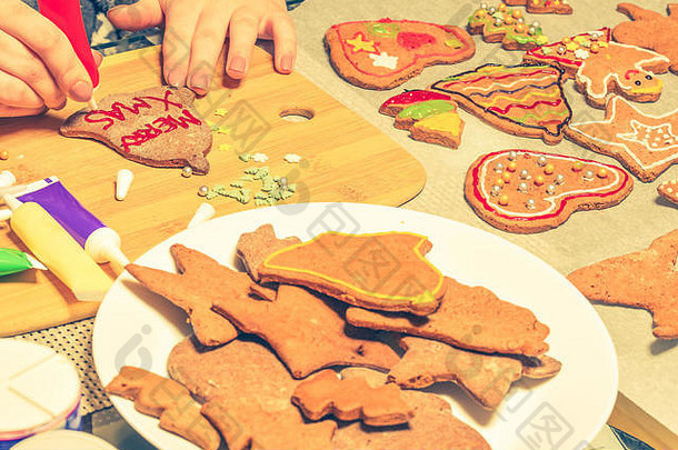 多彩的圣诞姜饼人和树饼干。展示手在饼干上做装饰。圣诞节的概念。
