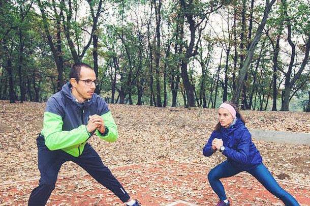 运动男人。女人温暖的锻炼公园适合年轻的夫妇培训秋天早....自然