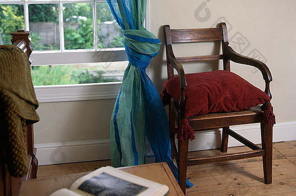 在90年代的卧室里，红色天鹅绒靠垫放在窗边的复古木椅上，蓝色 绿色的百叶窗帘