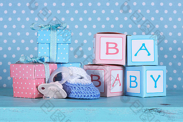 婴儿托儿所靴、假奶嘴和婴儿字母粉色和蓝色礼盒搭配复古水蓝色桌子