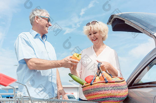 一位老人拿着购物车看着他的妻子