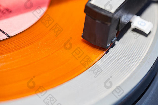 橙色乙烯基唱片特写镜头上的转盘头壳