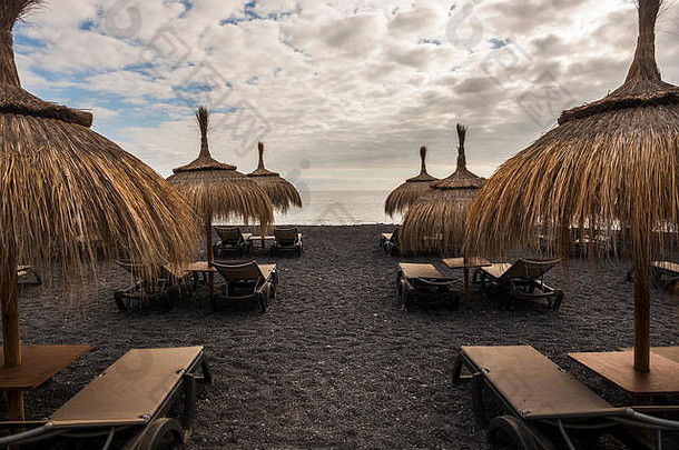 特内里费岛海滩上的雨伞和座椅。一个无人度假的地方。恶劣天气暂停营业