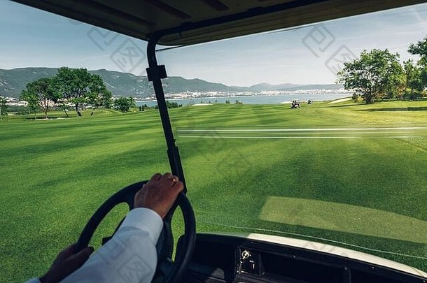 一个面目全非的男人在绿色高尔夫球场上骑着高尔夫球车