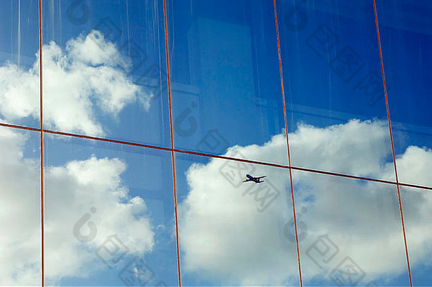 飞机的天空和云彩倒映在现代办公楼的窗户上