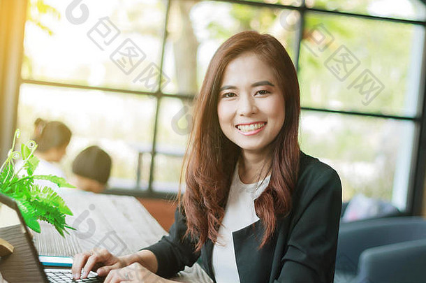 亚洲女商人使用笔记本电脑，女商人微笑着工作，轻松专注