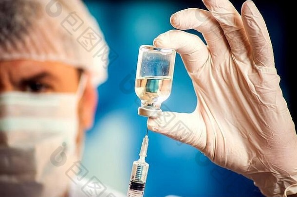 医生戴着医用手套，在注射前拿着装有疫苗和注射器的瓶子。特写镜头。医学、科学和保健概念