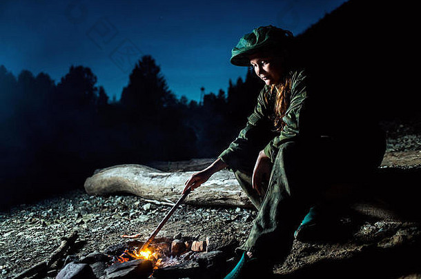 女孩在营火周围搅拌煤