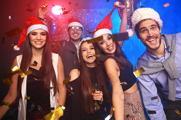 庆祝一年集团美丽的年轻的人圣诞老人帽子扔色彩斑斓的五彩纸屑快乐