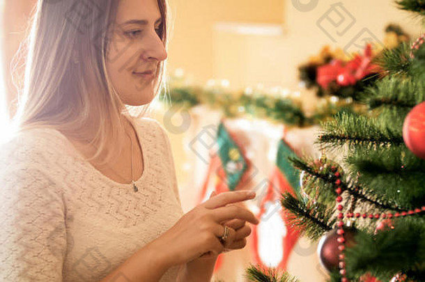 微笑的年轻女子坐在客厅里看着圣诞树的特写照片