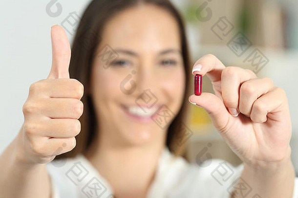 一个快乐的女人举起大拇指展示<strong>药</strong>物胶囊的特写镜头