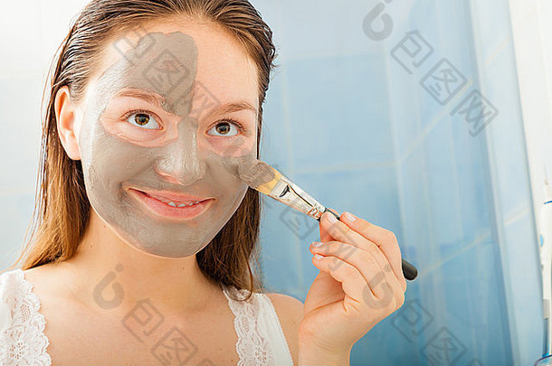 美容程序<strong>护肤</strong>理念。在浴室里，一位年轻女子在脸上涂上了灰色泥泥泥<strong>面膜</strong>