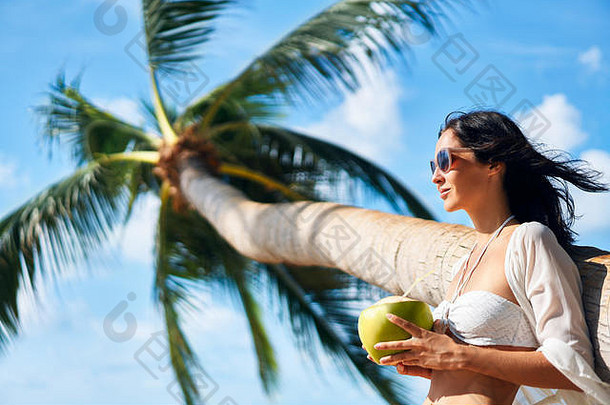 美丽的年轻的女人享受椰子喝放松热带海滩棕榈树夏天假期概念