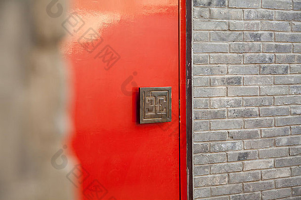 中国式把手上有符号的红门，灰色砖墙