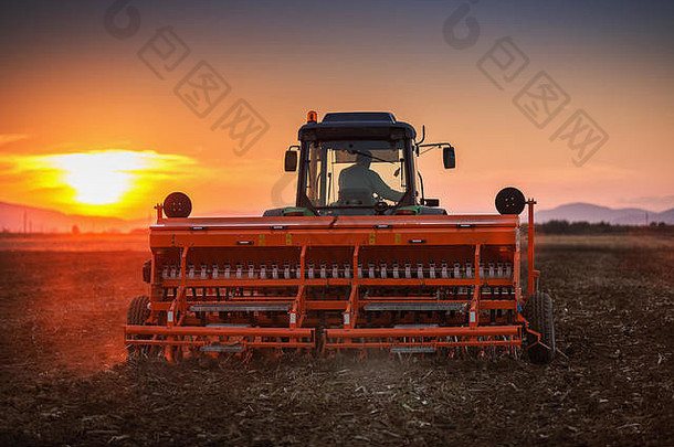 日落时，农民在田间用拖拉机播种作物