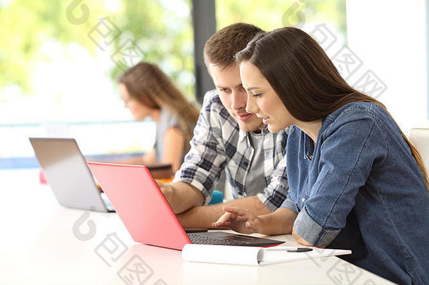 两个全神贯注的学生在教室里用笔记本电脑在线工作