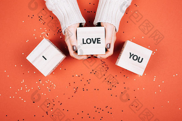 沃南的手拿着立方体，上面写着“我爱你”。平铺式。活<strong>珊瑚</strong>——2019年的颜色。