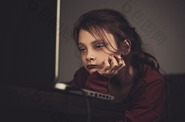 非常累，想睡觉，小女孩坐在家里看着电脑显示器。暗影特写复古色调肖像。