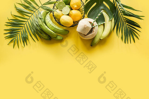 水果、香蕉、酸橙、棕榈叶的热带边缘，淡黄色背景。顶视图。夏日海滩度假。文本的空间。排毒之旅。