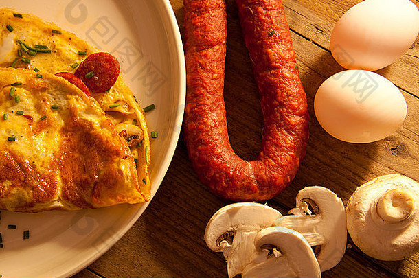 农舍餐桌上放着刚做好的蛋卷，里面装满了<strong>蘑菇</strong>和意大利腊肠，阳光明媚。