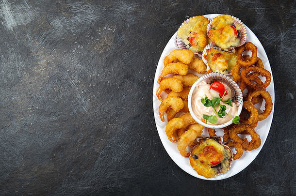 秘鲁食物。皮奎奥·卡连特。热海鲜拼盘炒虾、鱿鱼圈和酱汁烤扇贝