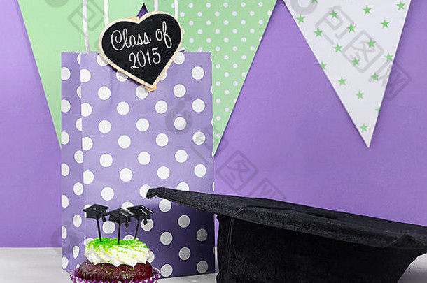 毕业日绿色和紫色<strong>主题派对</strong>，配有纸杯蛋糕和毕业帽。