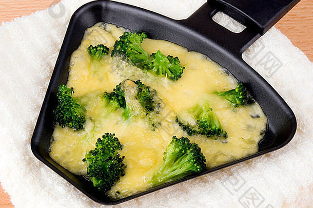 拉克莱特平底锅，奶酪和西兰花放在柔软的餐巾上