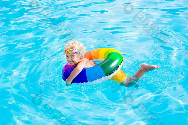 炎炎<strong>夏日</strong>，快乐的小男孩在室外<strong>游泳</strong>池里玩着五颜六色的充气戒指。孩子们学习<strong>游泳</strong>。儿童水玩具。儿童游戏