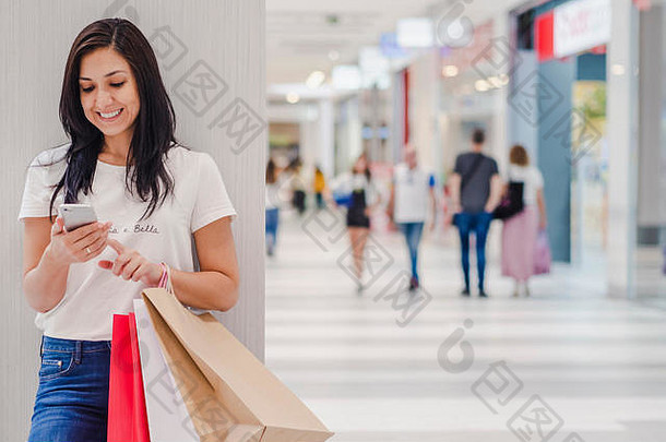 黑色的星期五女人智能手机持有购物袋站购物中心背景水平图像