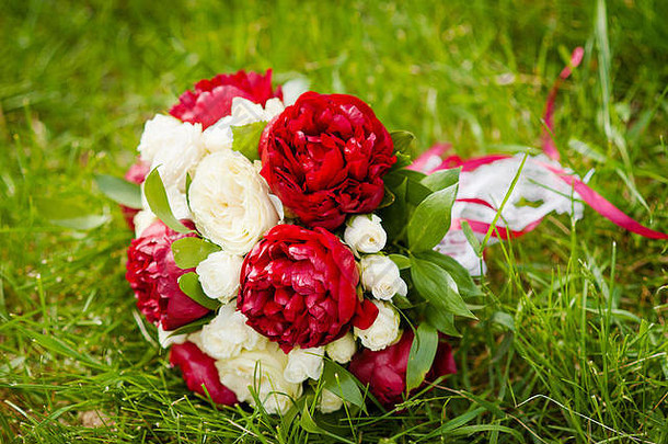 由勃艮第牡丹和白玫瑰制成的春季婚礼花束。婚纱照的概念。夏季婚礼。