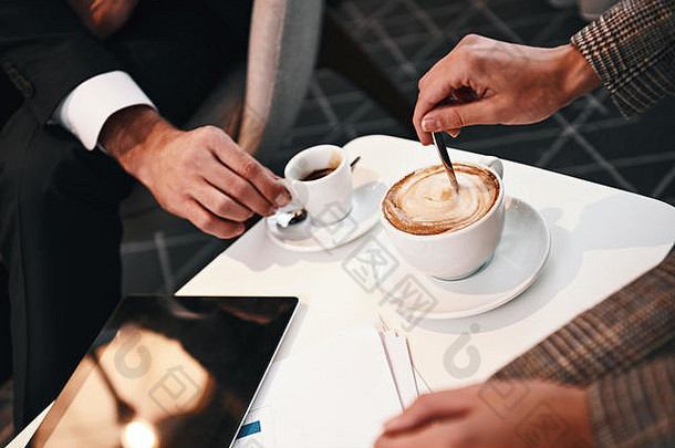 两个合作伙伴的商务会议。一对男女在餐厅喝咖啡吃商务午餐的特写镜头。桌上的数字平板电脑