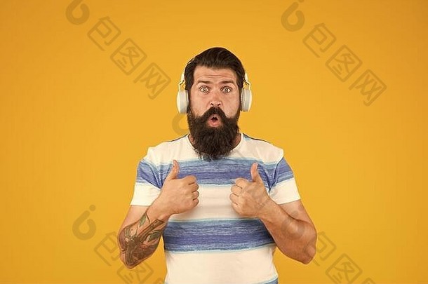 放松的旋律。夏季播放列表。暑假音乐。暑假穿条纹衬衫的家伙。留着胡子、留着长胡子的时髦男人，戴着黄色背景的耳机听歌曲。