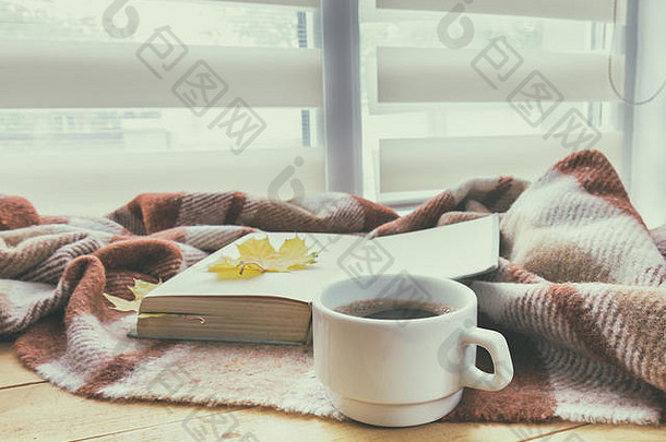 一杯咖啡和一本书，秋天的黄叶环绕着窗台上的毛毯