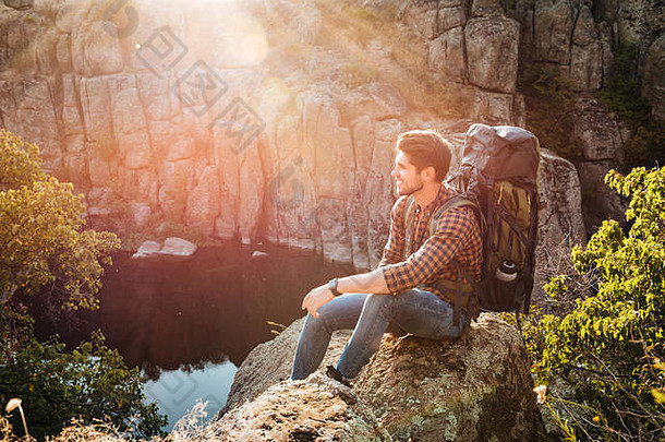 <strong>冒险者</strong>坐在峡谷附近的岩石上。看着别处。侧视图