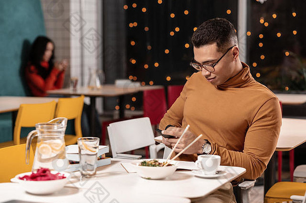 一名拒绝吃饭的男子一边坐着一边用智能手机聊天。