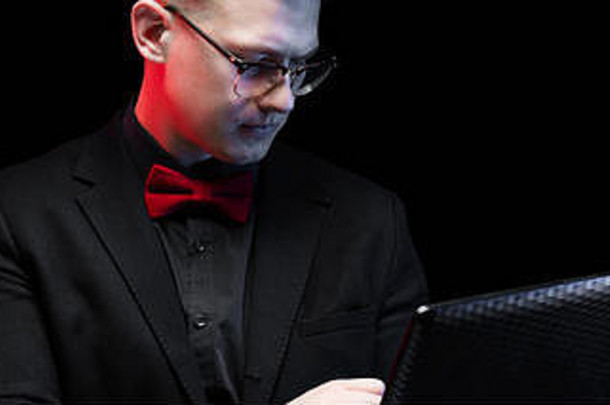 自信、英俊、雄心勃勃、快乐、优雅、负责任的商人在黑色背景下操作笔记本电脑的肖像
