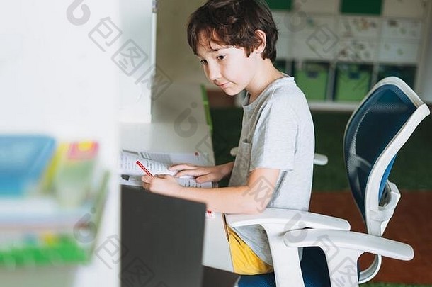 在教室里用打开的笔记本电脑做家庭作业，在学生课本上学习外语写作，家庭听写教育